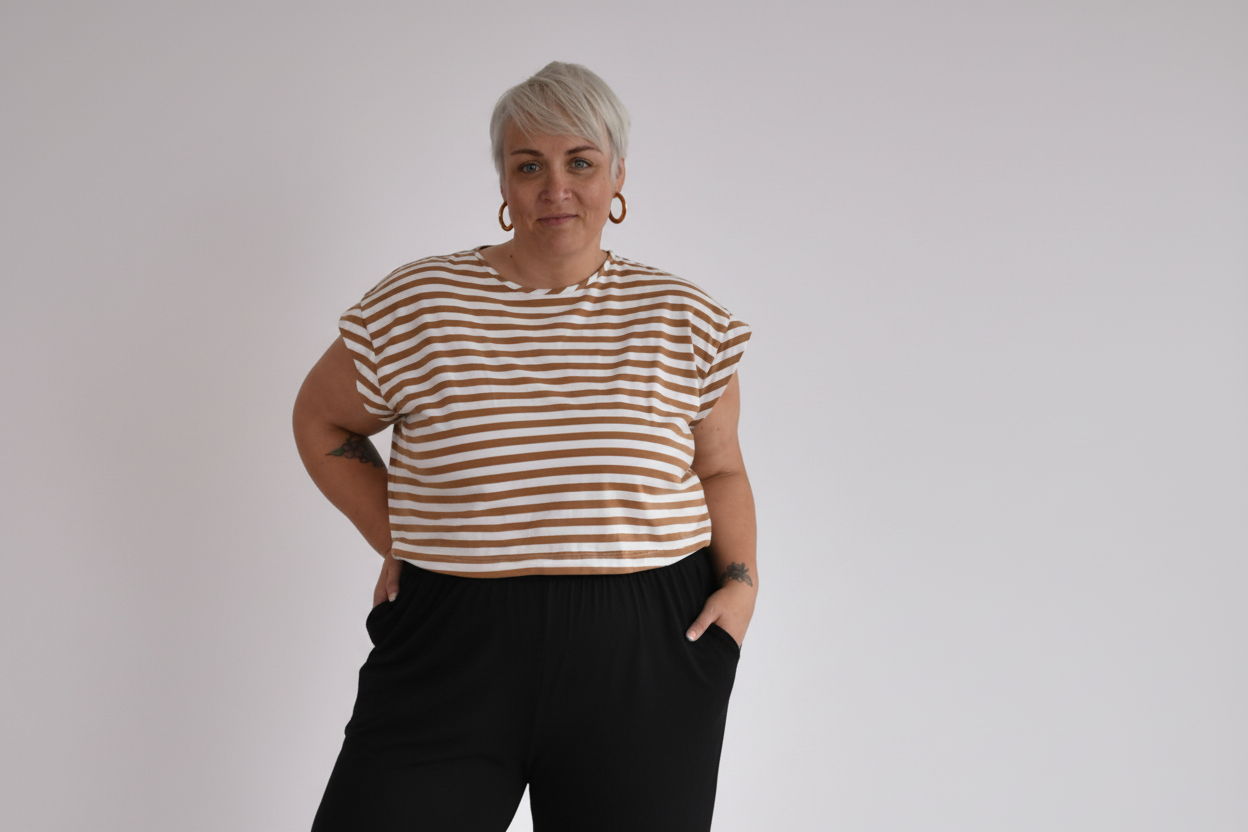 Woman wearing a striped shirt and black pants against a plain background
