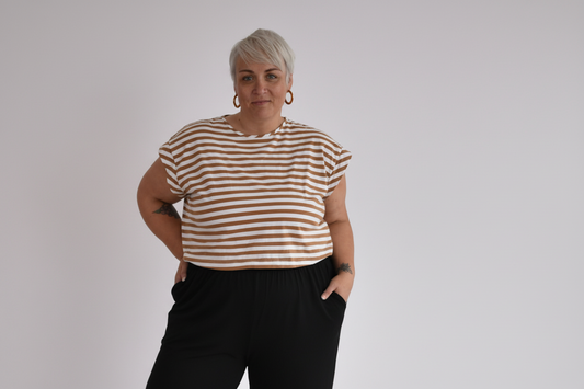 Woman wearing a striped shirt and black pants against a plain background