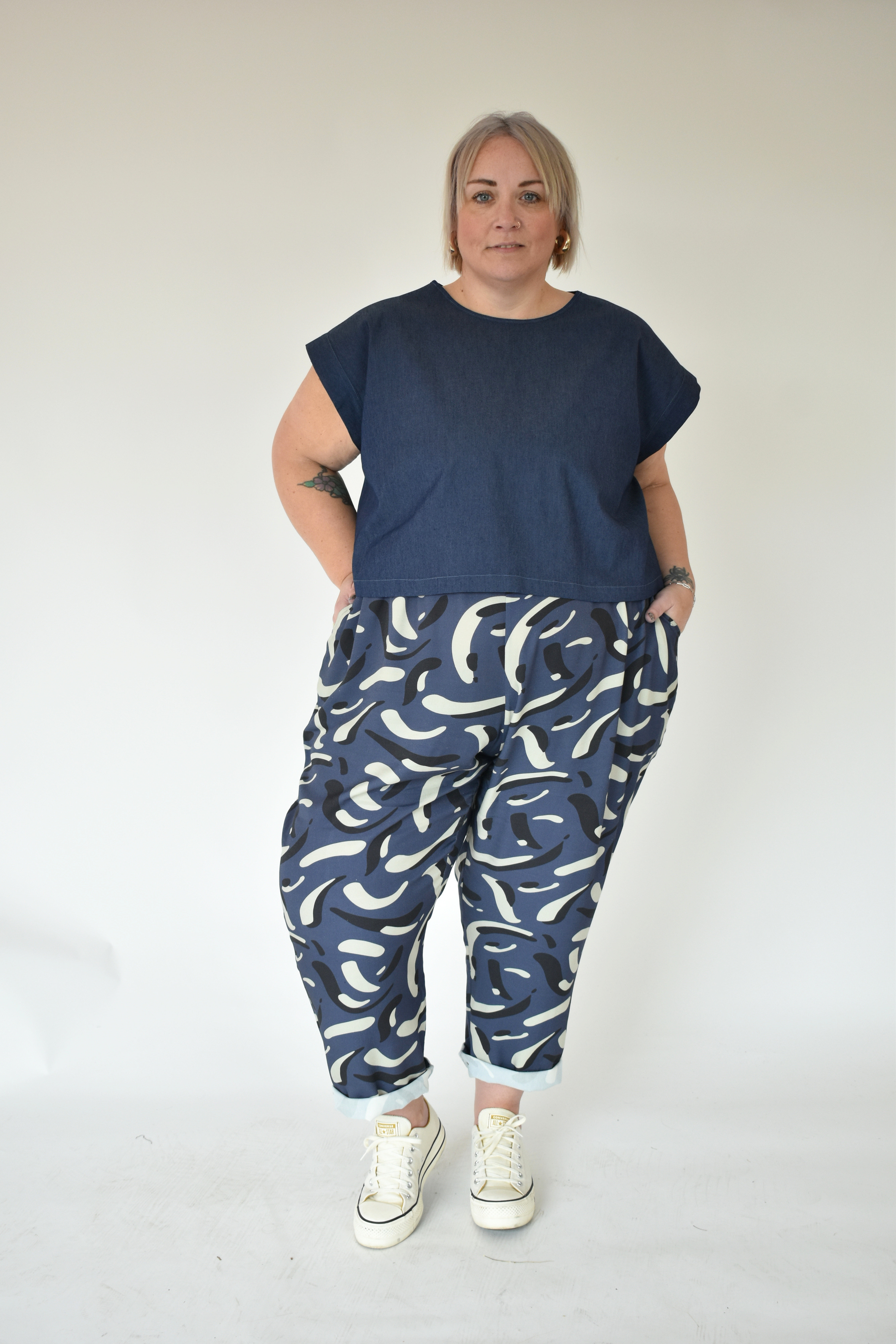 Person wearing a navy t-shirt and blue patterned pants on a white background