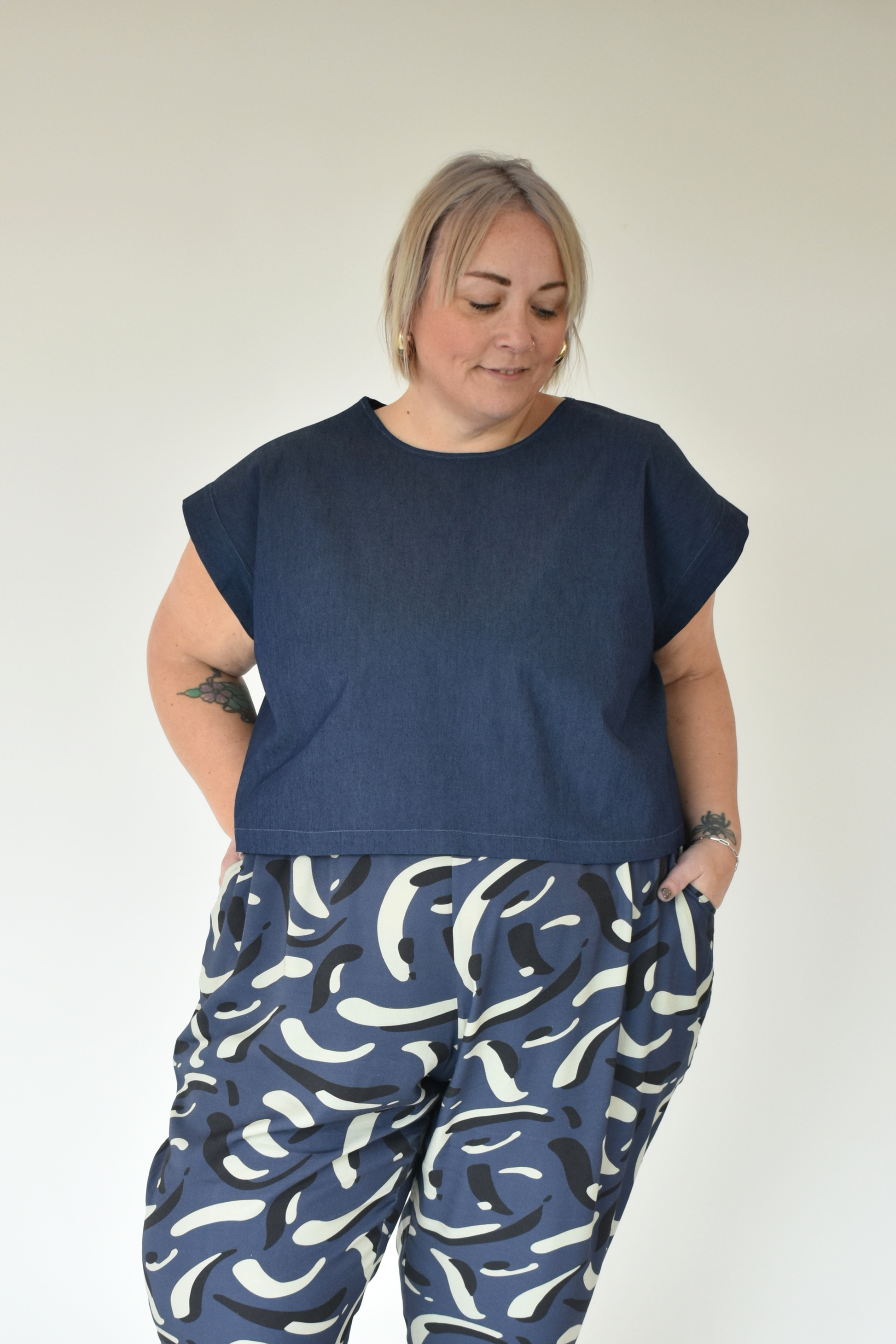 Person wearing a navy top and blue patterned pants against a white background