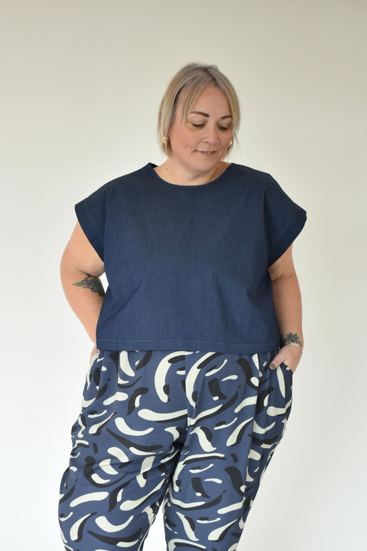 Person wearing a navy top and blue patterned pants against a white background