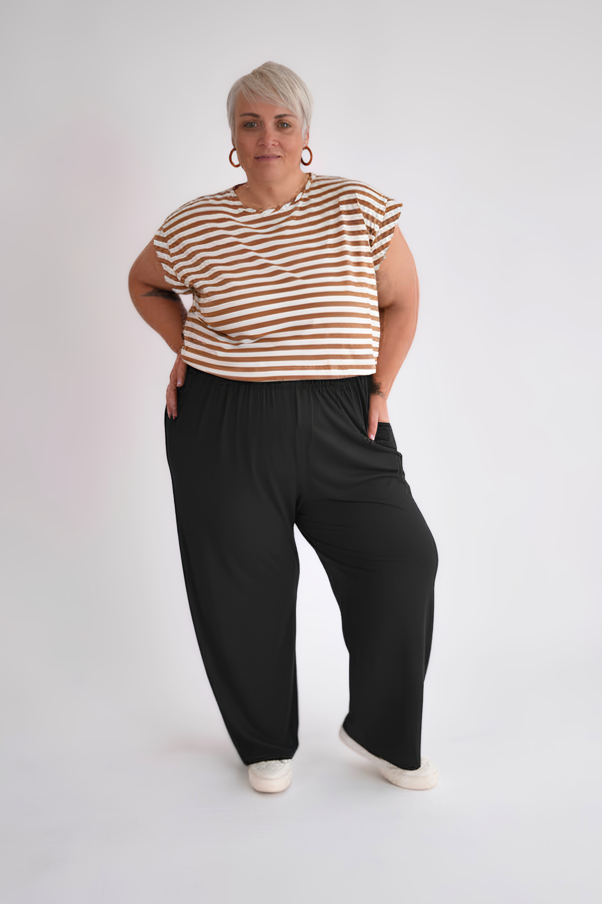 Person wearing a striped shirt and black pants on a white background